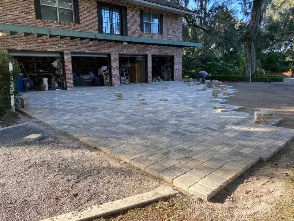 A new paver driveway in front of a brick home with a three-car garage