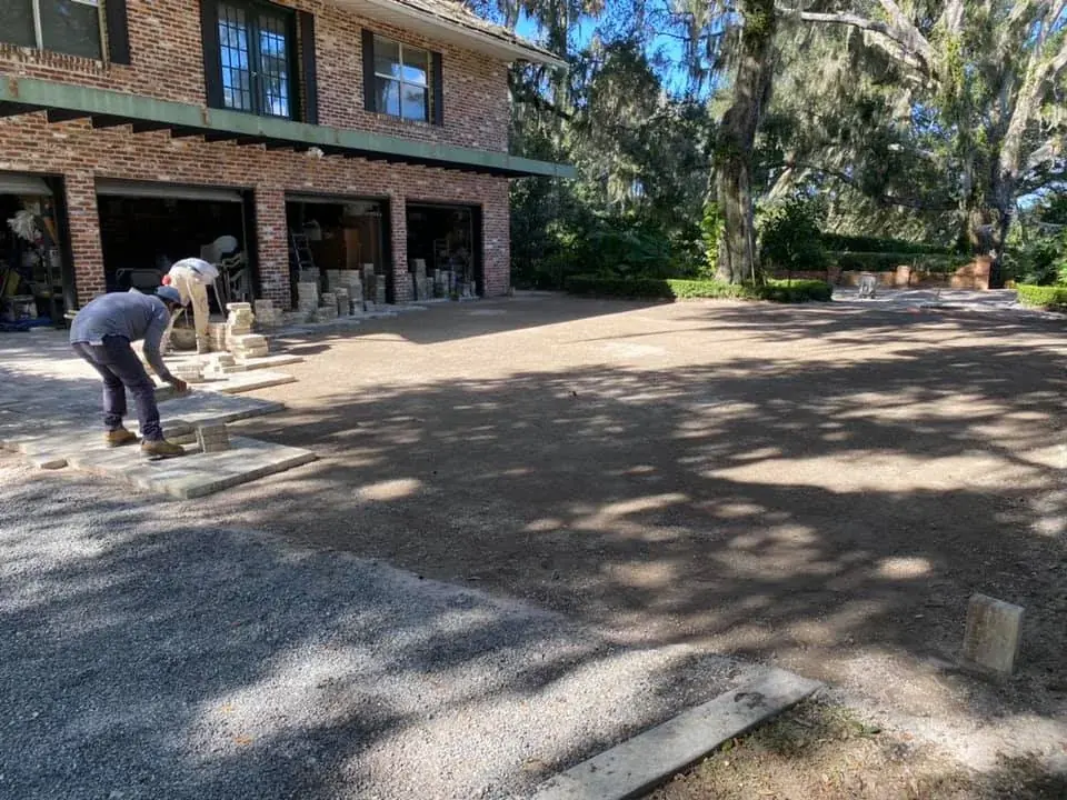 The crew laying a paver driveway under oak trees