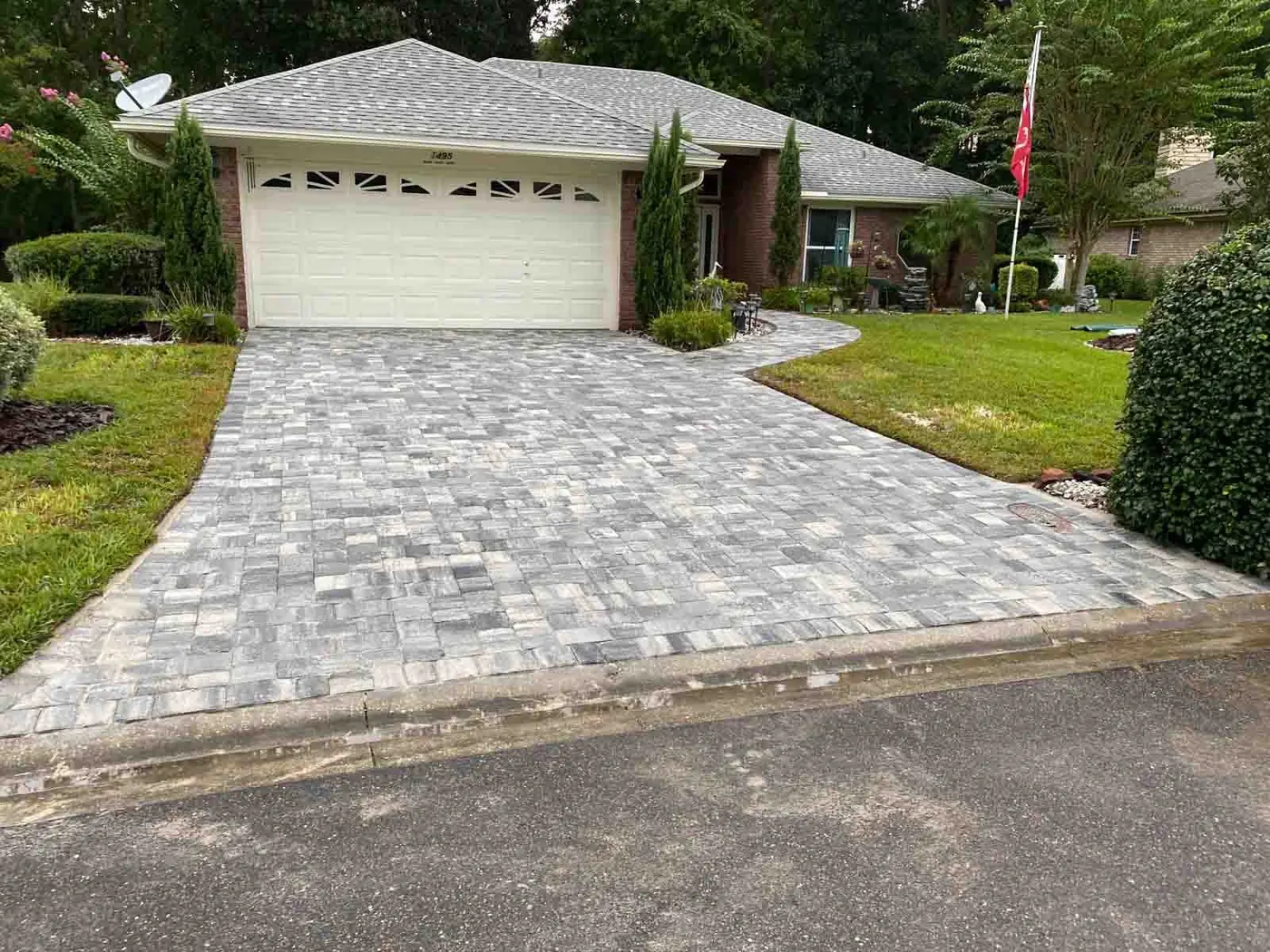 A paver driveway leading to a two-car garage