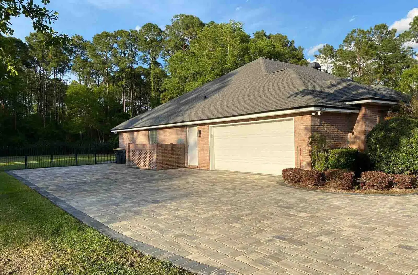 A wide paver driveway beside a brick home with a side-entry garage