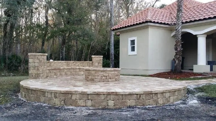 A round raised paver patio with a stone seating wall