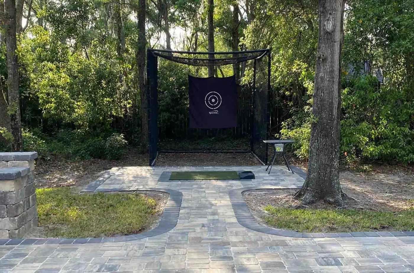 Paver paths around a practice net among the trees