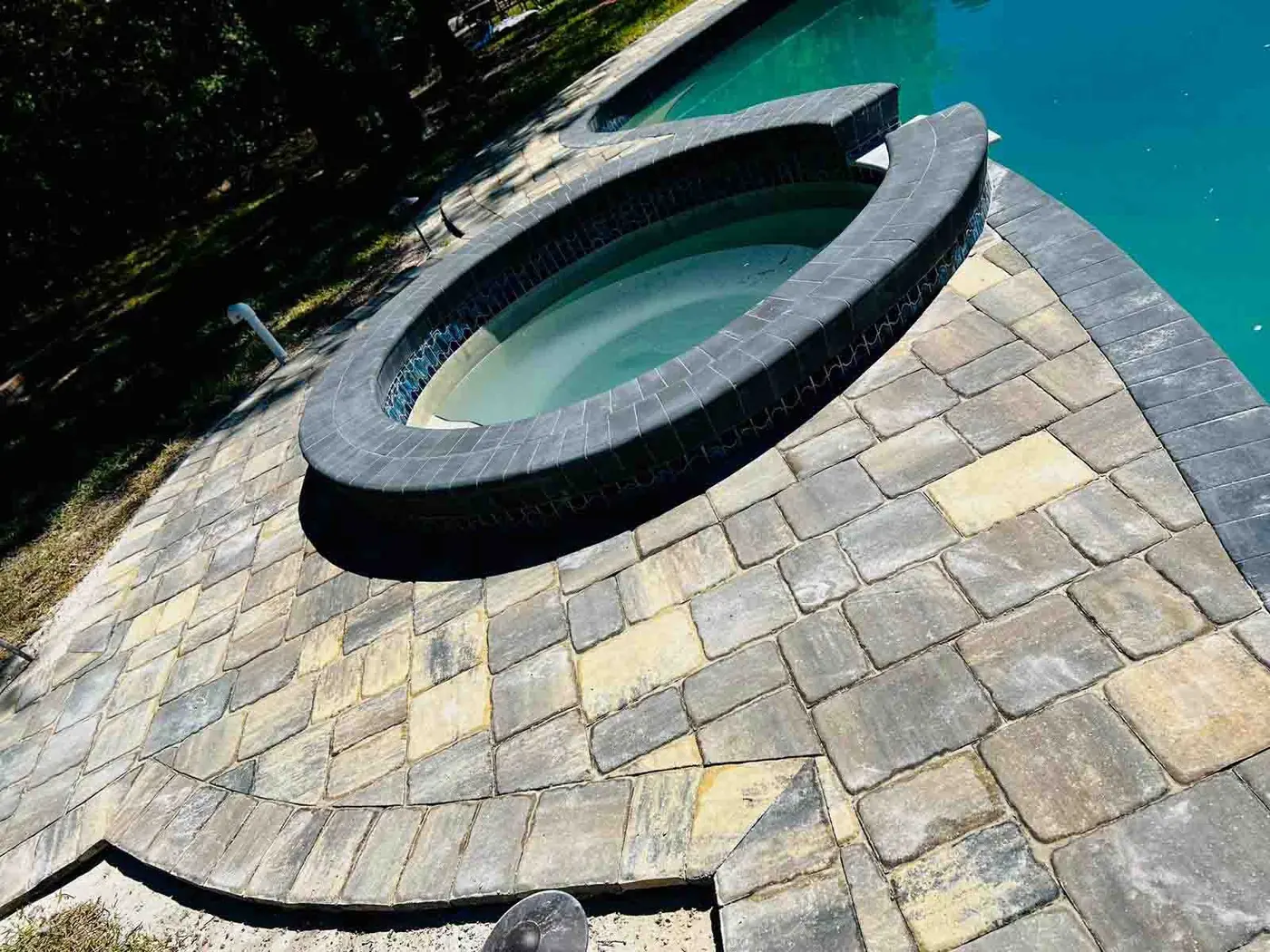 Paver detail around a raised spa at the edge of a pool