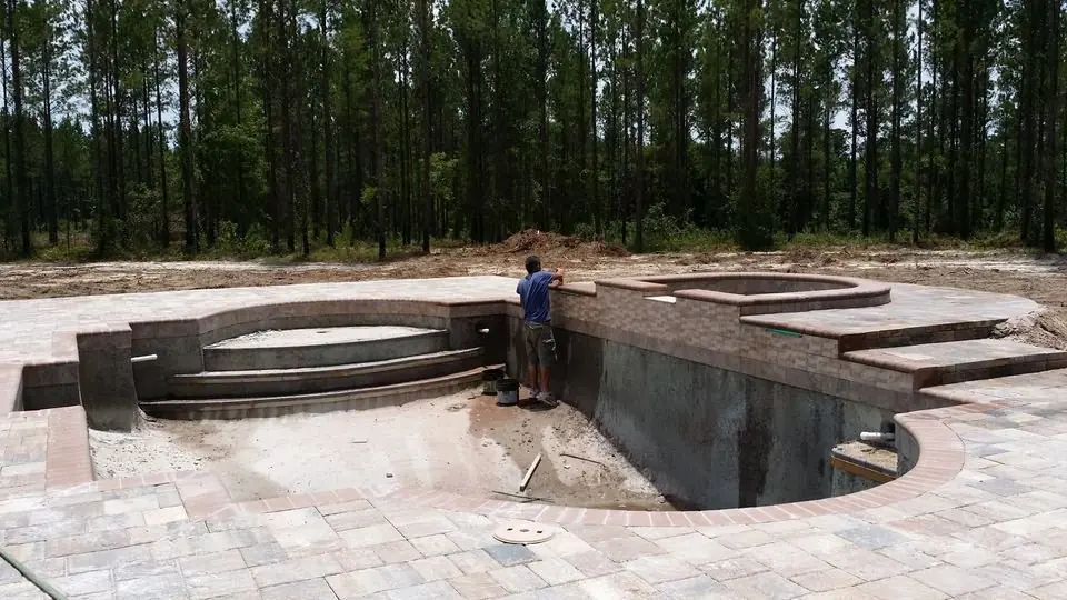 A pool under construction with its new paver deck