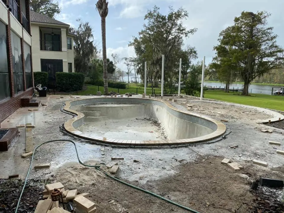 A paver deck being laid around a freeform pool